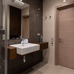Sleek bathroom interior with a modern sink, mirror, and wooden door. Minimalist design focus.