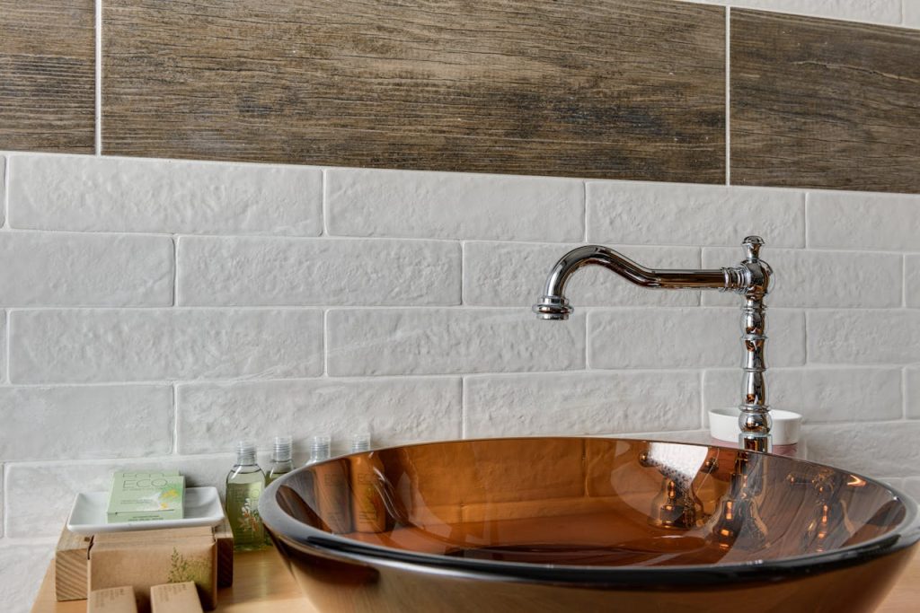Elegant bathroom interior featuring a glass bowl sink with sleek chrome faucet and stylish tile backdrop.